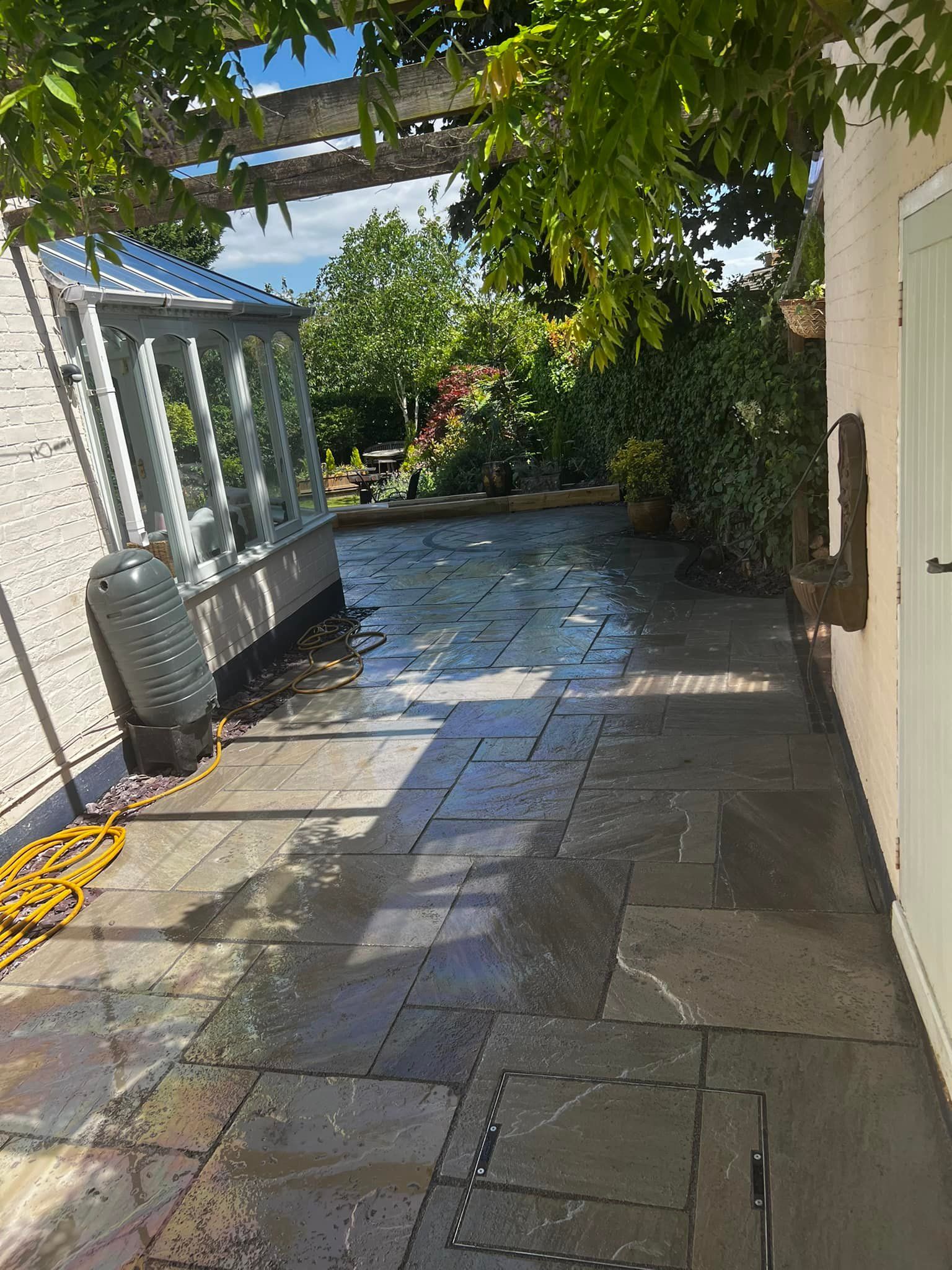 Finished sandstone patio alongside a period greenhouse